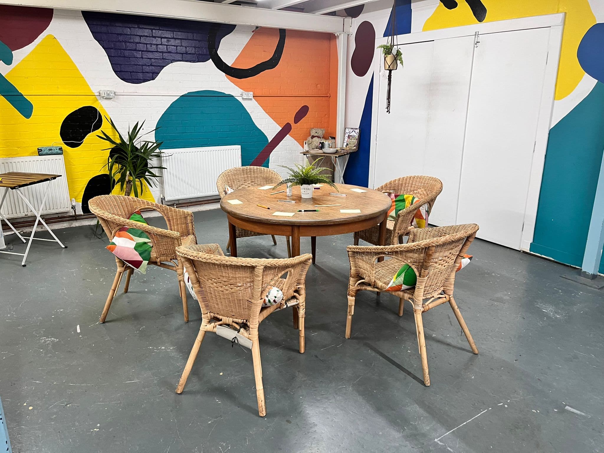 The plenary space set with wicker chairs around a round table in front of a bold abstract wall mural.