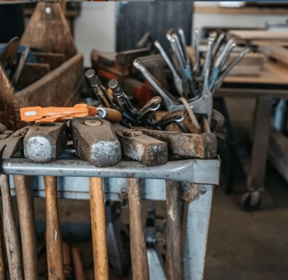Hammers and other hand tools stored on a metal rack in the workshop.