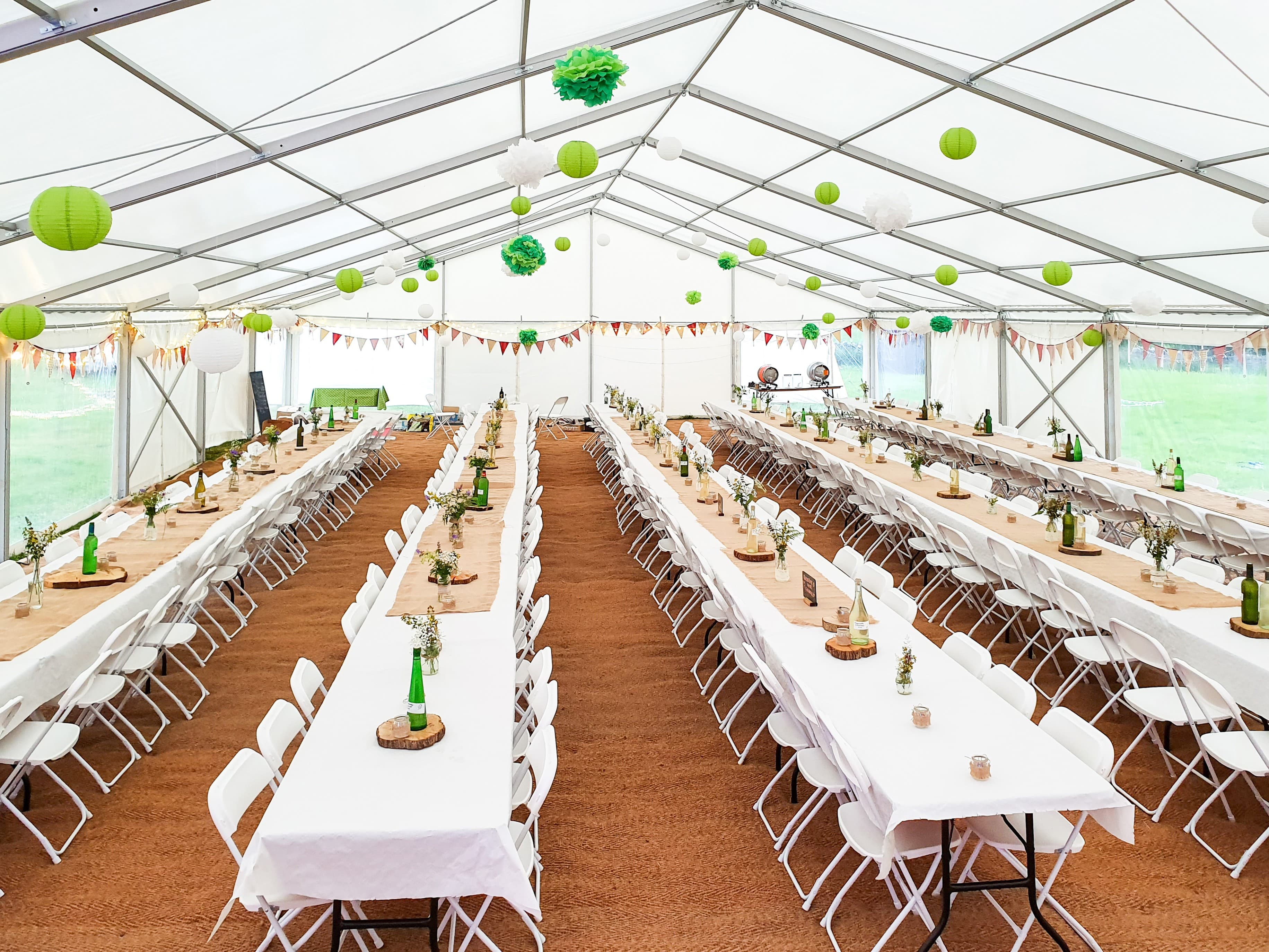 wedding setup in a clearspan marquee, furniture and decor including mat flooring, tables and chairs, flower decorations