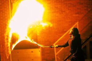 A person cracking a fire whip, displaying a big fire blast!