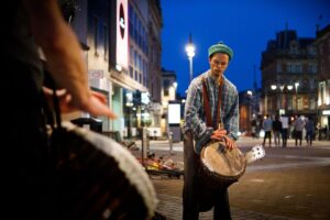 A drummer drumming as night falls in the street