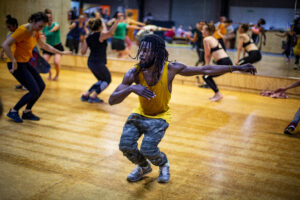 Lots of people captured mid-dance in a studio wearing bright colours