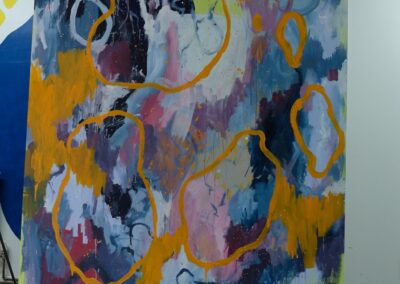 A large abstract painting on display by Niko. The canvas features bold swirls and splashes of color—deep blues, purples, and pinks—overlaid with looping orange outlines. The style is expressive and gestural, giving the impression of cosmic or organic forms.