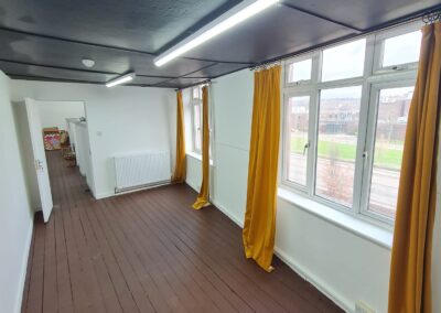 well lit empty lockable studio room, with brown wooden floorboards and yellow curtains that reach all the way to the floor
