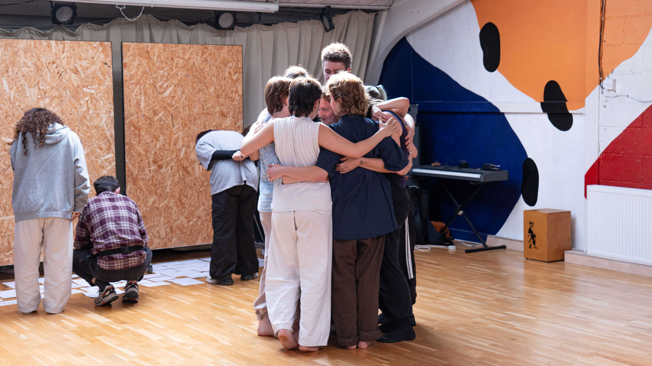 All the dancers from Magdalena's, around Magdalena in a group hug after their performance in the dance studio